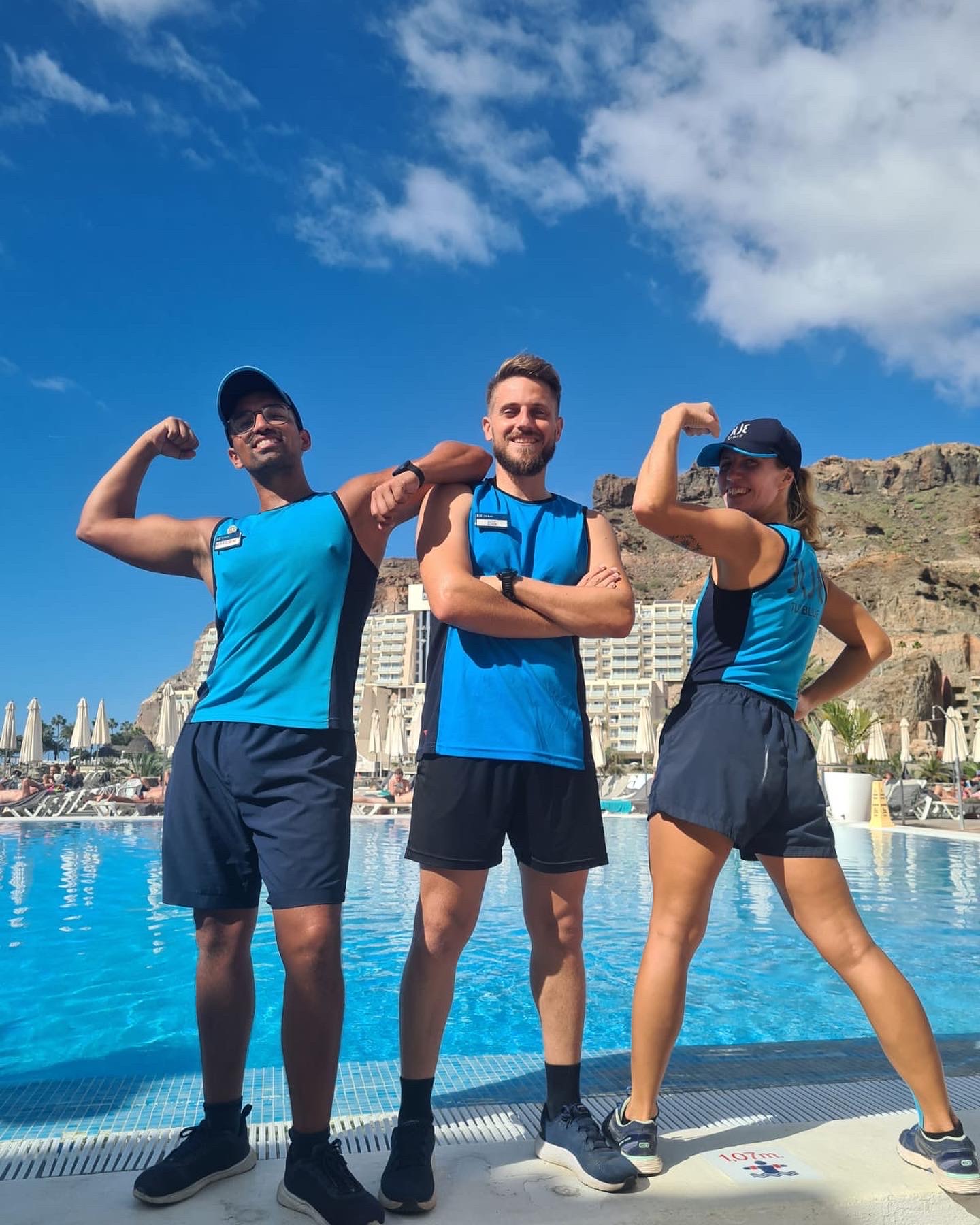 3 Fitness Instrukteure posieren in TUI BLUE Uniform vor einem Pool
